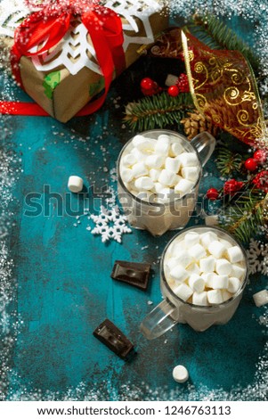 Hot Chocolate with Marshmallows and Christmas Gift on a blue stone or concrete table. Copy space.