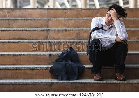 Unemployed stressed young Asian business man in suit covering face with hands. Failure and layoff concept. Royalty-Free Stock Photo #1246781203