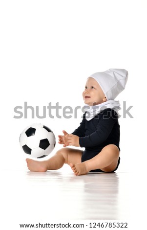 little boy having fun, holds a black and white football in his hands. wearing a white cotton hat and a black bodysuit