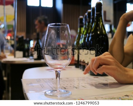  Wine glass wit hands and blurry wine bottles in background in French Independent winemakers of France (Salon du vin) in Pairs celebrate of 40th years in 2018