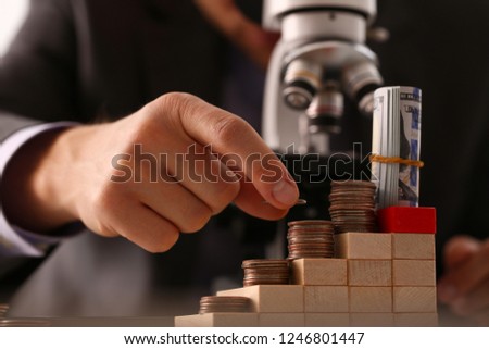 Hand businessman in suit hold quarter in background looking through microscope closeup search business concept Royalty-Free Stock Photo #1246801447