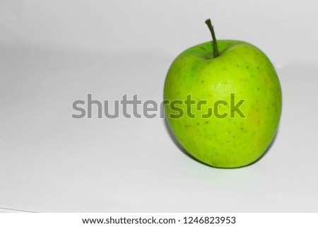 Green apple stands on a gray background on the right