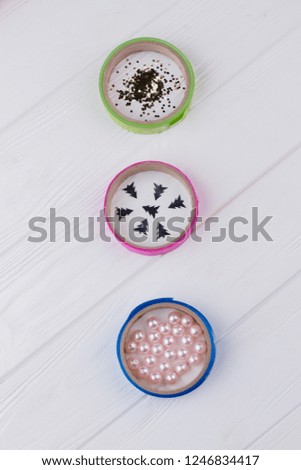 DIY Christmas ornaments. Three colorful ribbon rolls with Christmas glitter particles on wooden background. Childrens art project. DIY concept.