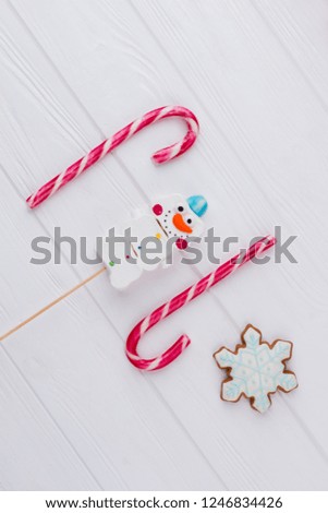 Biscuits and candies for winter holidays. Candy canes, marshmallow snowman candy and snowflake cookie. New Year holiday decor.