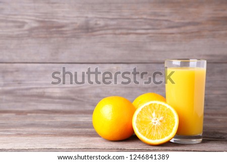 Glass of orange juice with orange on a grey wooden background