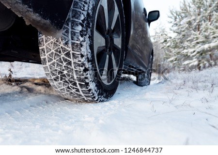 Car tires on winter road covered with snow. Vehicle on snowy way in the morning