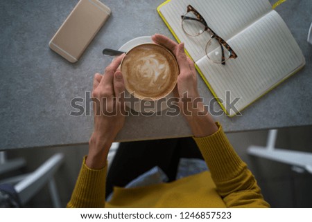 Female hands holding cup of coffee on table background. Coffee cup in coffee shop. Closeup image woman drinking hot coffee in cafe. Vintage style effect picture. Selective focus.