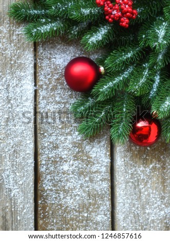 Christmas background for greeting card with Christmas tree branches, decoration and red balls, on on dark wooden board. Top view with copy space for text.