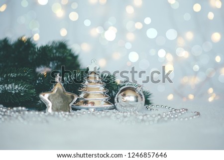 Christmas background with a silver decorations and fir in snow on the blurred, sparkling background. Toned image with copy space. Selective focus.