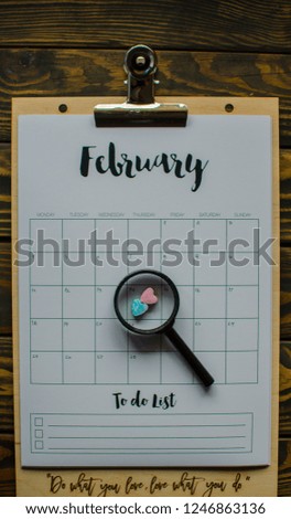 date planning, appointment, deadline or holiday concept on wooden table next to  clean calendar on month of February