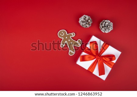 Christmas gift box present on red background with ribbon bows and festive holiday decorations. Horizontal bottom border. Top view with copy space
