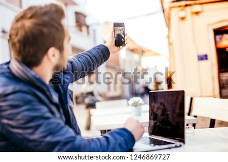 Man using smartphone technology in everyday life, taking selfies and editing pictures