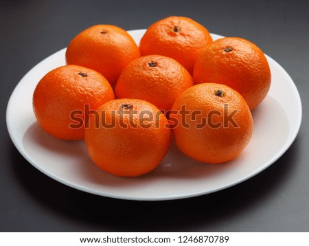 ripe tangerines in a white plate on a black background
