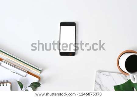 Top view office desk. Workspace with mockup smartphone, keyboard and office supplies, pencil, green leaf with coffee on white background.