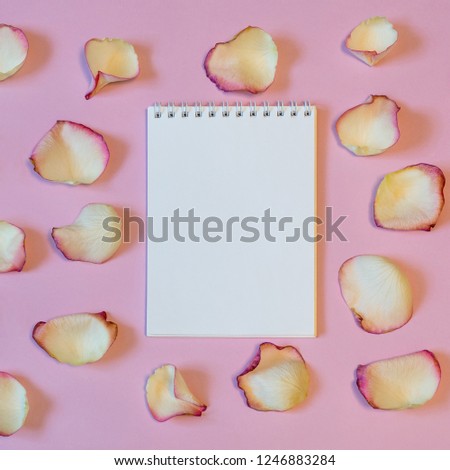 Notebook with dried cream rose petals on pink pastel paper background. Love or romance concept, mock up. Flat lay, copy space, top view