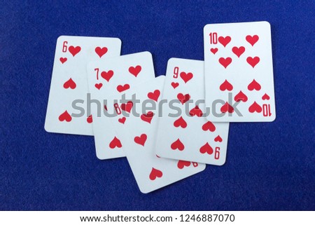 The combination of cards straight flush of hearts, on the blue fabric of the gaming table