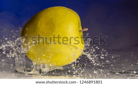 Green apple and splashes of water on a colored background