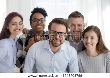 Portrait of smiling millennial multiracial office workers posing together, diverse young business people standing looking at camera, team of professionals show support and unity. Teamwork concept