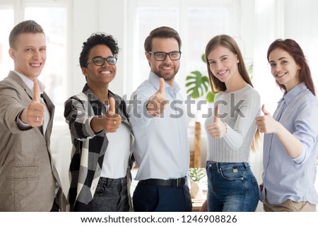 Happy millennial multiracial people standing together showing thumbs up sign, smiling young employees or workers make gesture recommending good service, diverse colleagues give recommendation