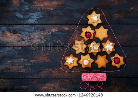 Christmas tree made from gingerbread cookies with toys and red ribbon on old wooden vintage background. New Year card. Top view with space.