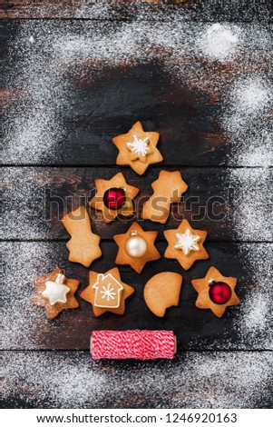 Christmas tree made from gingerbread cookies with toys and red ribbon on old wooden vintage background. New Year card. Top view with space.