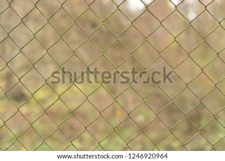 Rusty wire fence in the garden with blurry background. 
