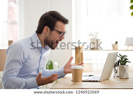 Mad male worker lose temper scream loudly having computer problems or virus attack, furious man shout experience laptop breakdown or data loss while working, angry employee get error message on pc Royalty-Free Stock Photo #1246921069