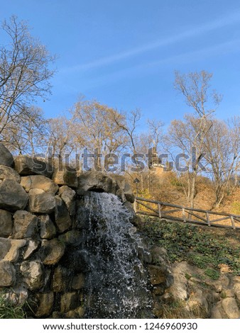 Small waterfall in the autumn park with a church on the background