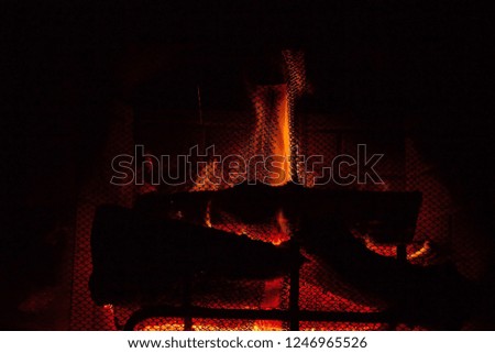 A beautiful wood fire  behind a black chain fireplace screen.