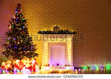White decorated fireplace near christmas tree on brick wall background