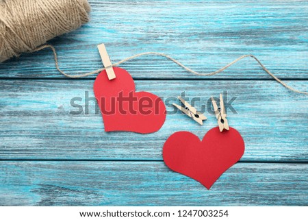 Red paper hearts hanging on rope on blue background