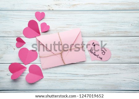 Pink paper hearts with envelope on wooden table