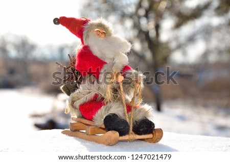 Toy Santa Claus on a sled in the snow outdoors.