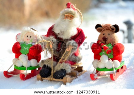 Christmas toys Santa Claus, angel, bear on a sled ride through natural snow.