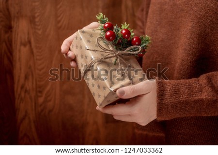 Woman hands holding Christmas handmade gift box decorated with mistletoe