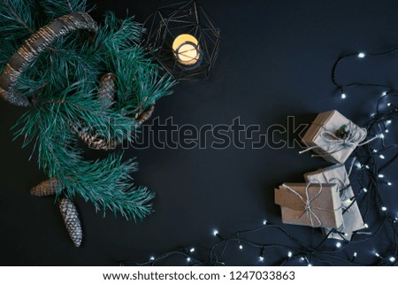 Gift boxes, garland and basket with christmas tree branches on dark background.