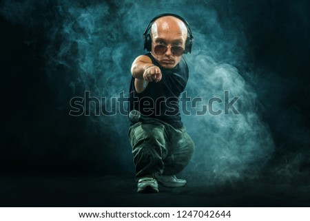 Portrait of stylish midget MC in with headphones and sunglasses posing with microphone. Royalty-Free Stock Photo #1247042644