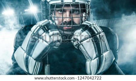 Ice Hockey player in the mask and gloves on stadium with stick.