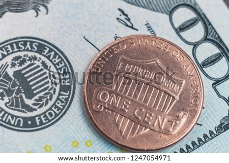 Macro photo of one cent and 100 US dollars on the background. Reverse american coin 2016 face value 1 cent photographed very close.