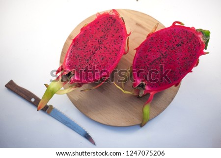 Exotic ripe pink Pitaya or Dragon fruit. Red Pitahaya tropical fruit cut in half on wood with a knife