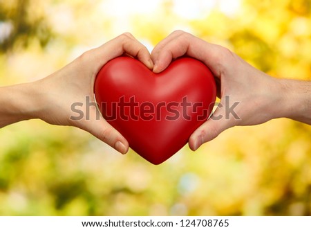 Red heart in woman and man hands, on green background Royalty-Free Stock Photo #124708765