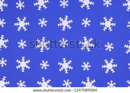 Pattern of white big and small snowflake confetti on blue background creating festive winter mood. Christmas and New Year celebration concept.