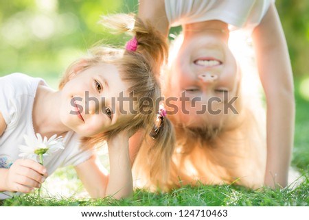 Happy children playing on green grass outdoors in spring park. Healthy lifestyles concept