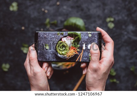 Photographing food. Hands taking picture of delicious vegetable salad with smartphone