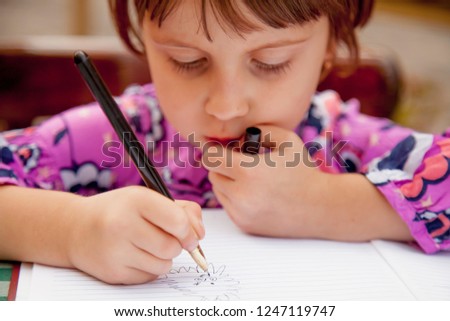 Humorous portrait of little female artist designer draws a pencil sketch  on notebook (creativity, art, training concept)
