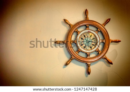 Concept: travel, sea navigation. Ship's nautical steering wheel and old compass on a light background with copy space.