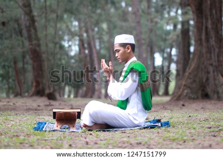 Young man praying and reading the Holy Quran in the open air