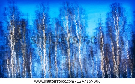 Winter blurred background with reflection of the trees  in the water of the ice-free lake