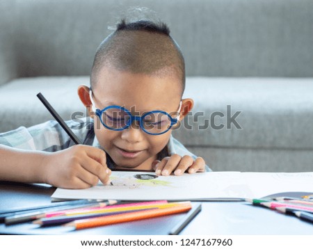 Boy intend drawing a picture fun, enjoy drawing or write in book at home.