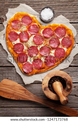 Heart shaped pizza with pepperoni and mozzarella. Valentines day greeting card. Top view